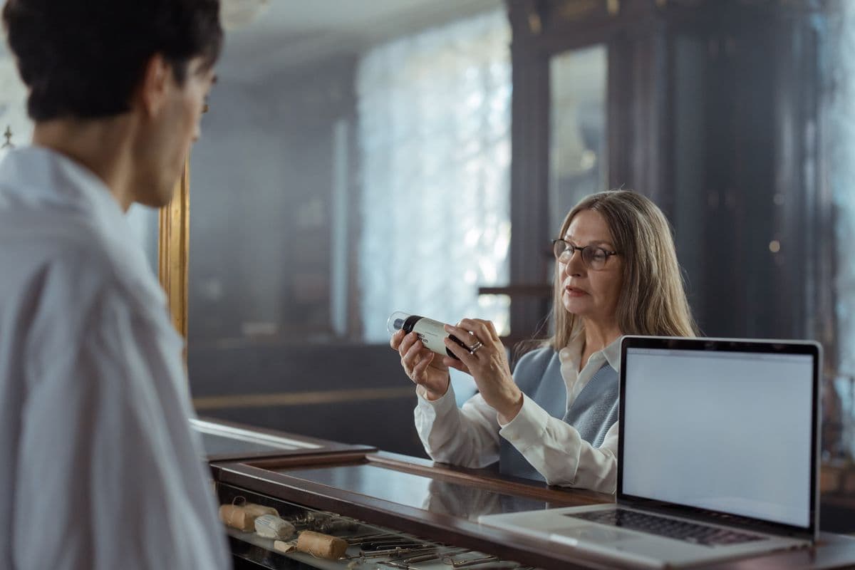 A pharmacist showing a medication bottle to a senior patient at the pharmacy counter