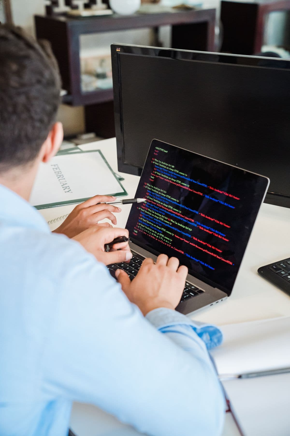 A software developer writing code on a laptop